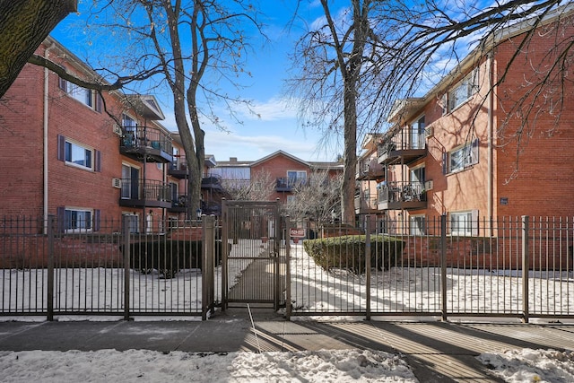 snow covered gate featuring a residential view and fence