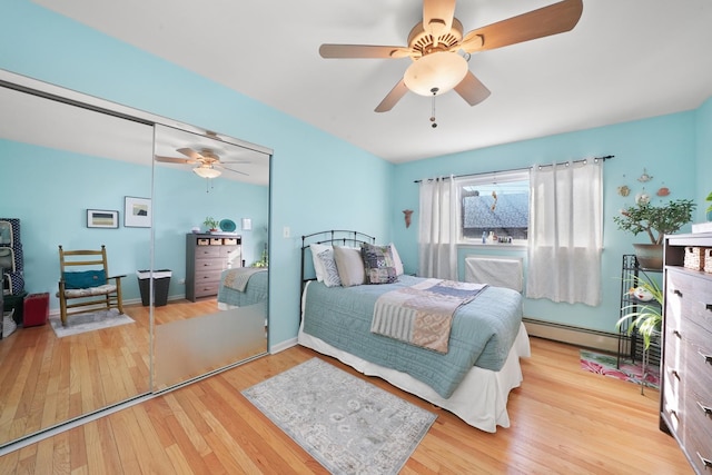 bedroom with wood finished floors, baseboards, a baseboard radiator, ceiling fan, and a closet