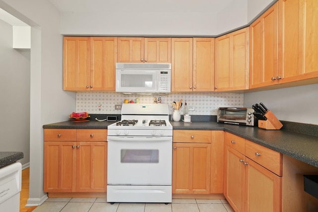 kitchen with white appliances, light tile patterned floors, a toaster, dark countertops, and backsplash