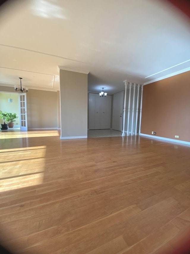 interior space with baseboards, wood finished floors, a chandelier, and ornamental molding