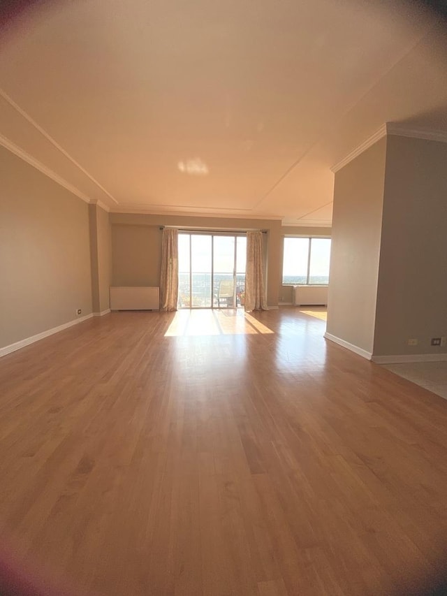 unfurnished living room featuring baseboards, wood finished floors, and ornamental molding