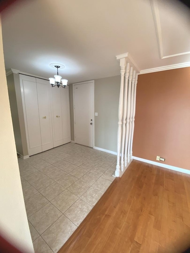 unfurnished room featuring baseboards, a notable chandelier, light wood-style flooring, and crown molding