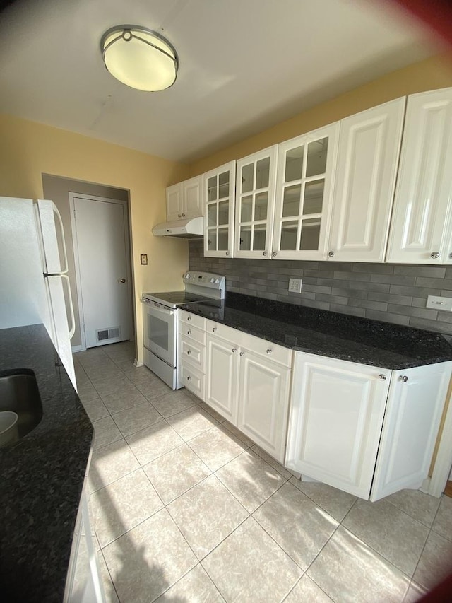 kitchen featuring tasteful backsplash, glass insert cabinets, under cabinet range hood, white cabinets, and white appliances