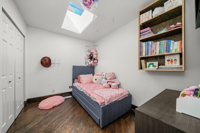 bedroom with a skylight, wood finished floors, baseboards, and a closet