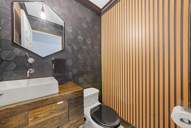 bathroom with toilet, vanity, ornamental molding, decorative backsplash, and tile walls