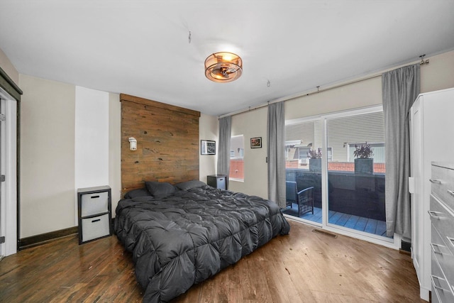 bedroom with visible vents, wooden walls, wood finished floors, and access to exterior