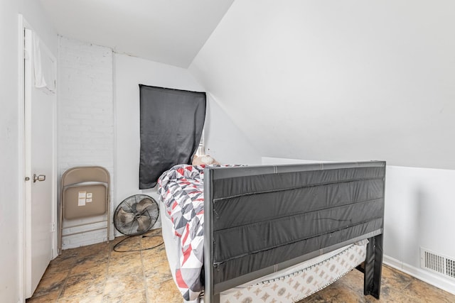 bedroom featuring stone finish flooring, visible vents, and vaulted ceiling