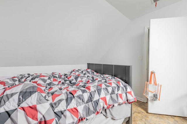 bedroom featuring stone finish floor and lofted ceiling