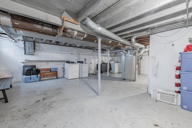 unfinished basement with electric panel, heating unit, and washing machine and clothes dryer