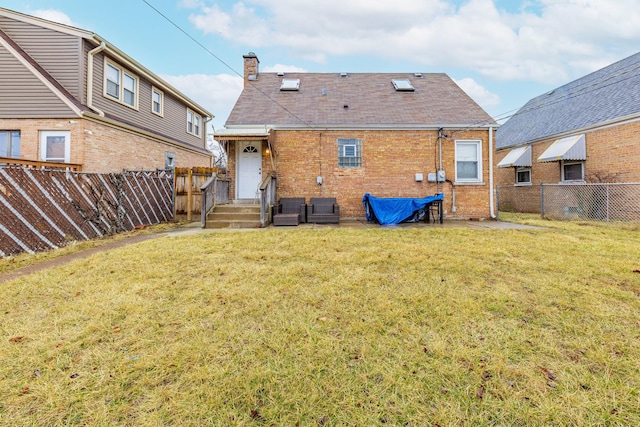 back of property with a lawn, brick siding, a fenced backyard, and a chimney