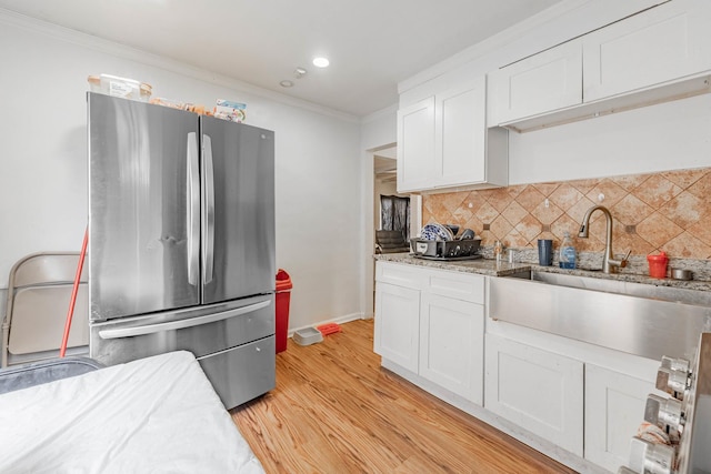 kitchen featuring freestanding refrigerator, light wood-style floors, white cabinetry, crown molding, and backsplash