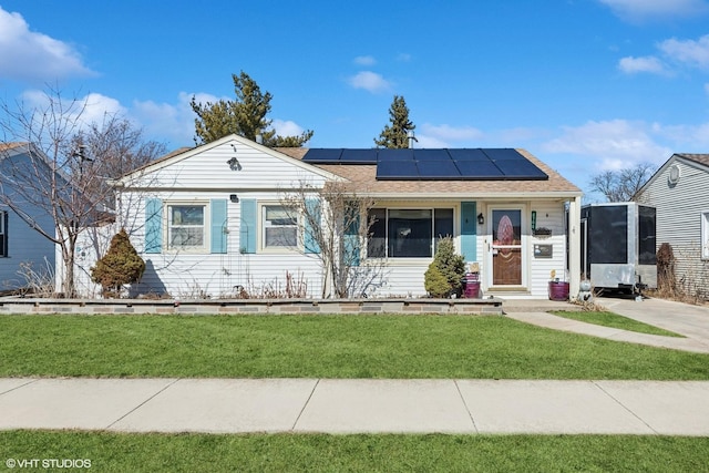 view of front of property with roof mounted solar panels, a front lawn, and roof with shingles