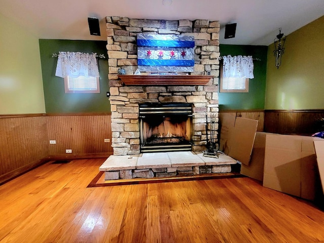 unfurnished living room featuring a fireplace, wood finished floors, a wainscoted wall, and wood walls