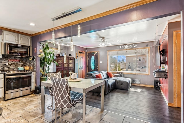 interior space featuring stainless steel range with gas cooktop, crown molding, decorative light fixtures, open floor plan, and backsplash