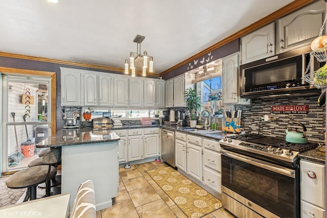 kitchen with a breakfast bar, a sink, decorative light fixtures, tasteful backsplash, and appliances with stainless steel finishes