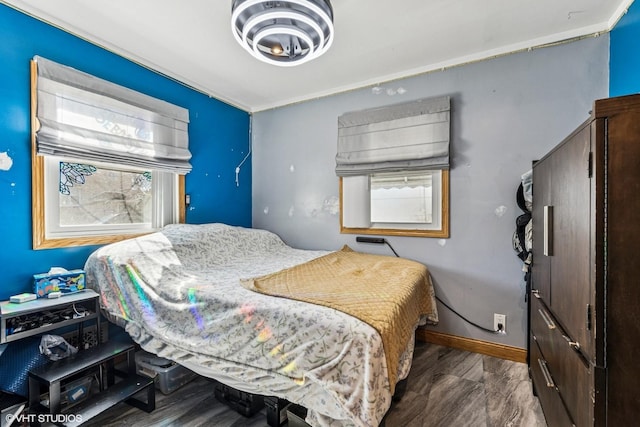 bedroom with multiple windows, baseboards, and wood finished floors