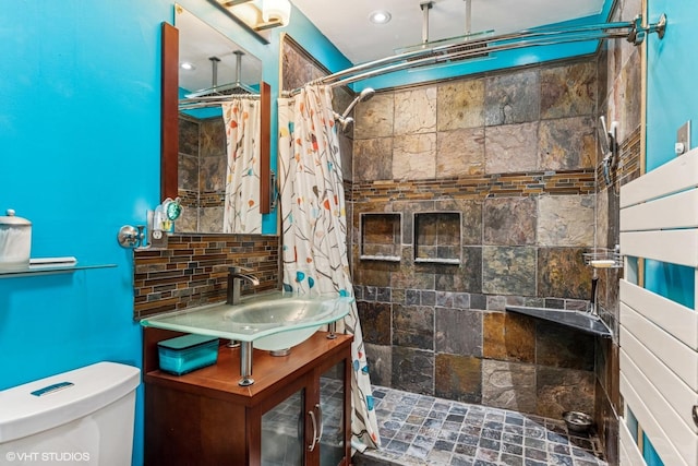 bathroom with vanity, toilet, a stall shower, and backsplash