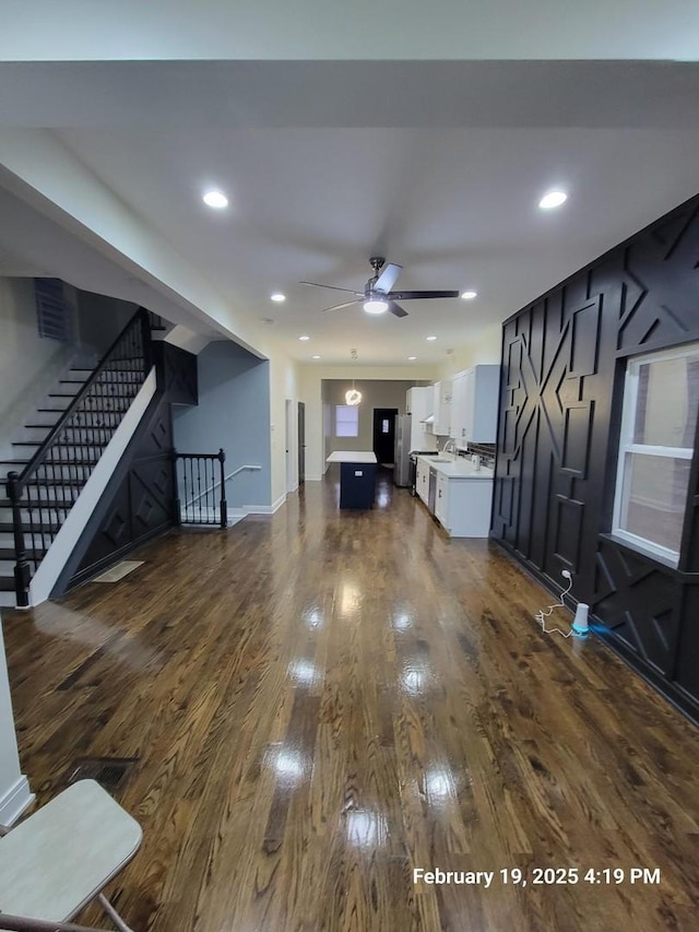 unfurnished living room with dark wood finished floors, stairs, recessed lighting, and baseboards