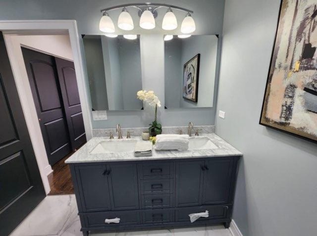 full bathroom featuring double vanity, marble finish floor, and a sink