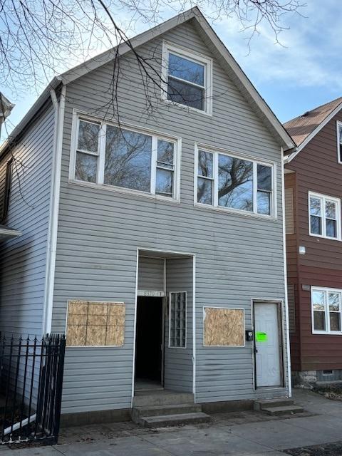 rear view of house with entry steps and fence