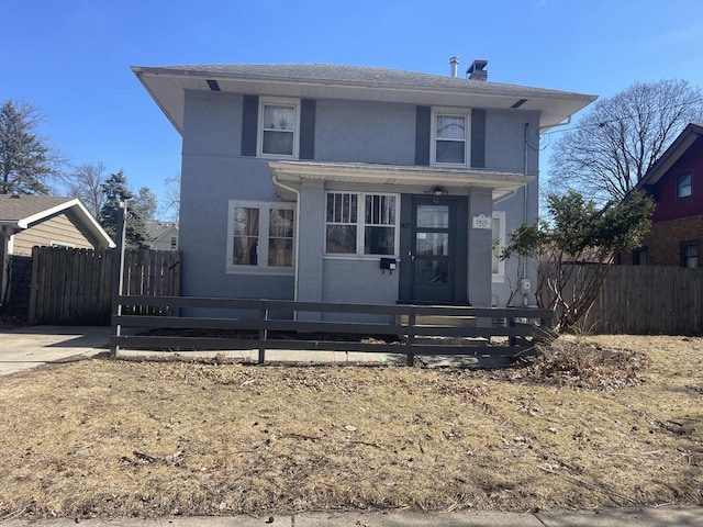 traditional style home featuring stucco siding, a porch, a fenced front yard, and a chimney