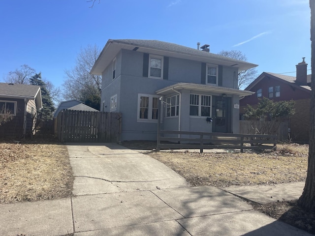 american foursquare style home with fence, driveway, and stucco siding