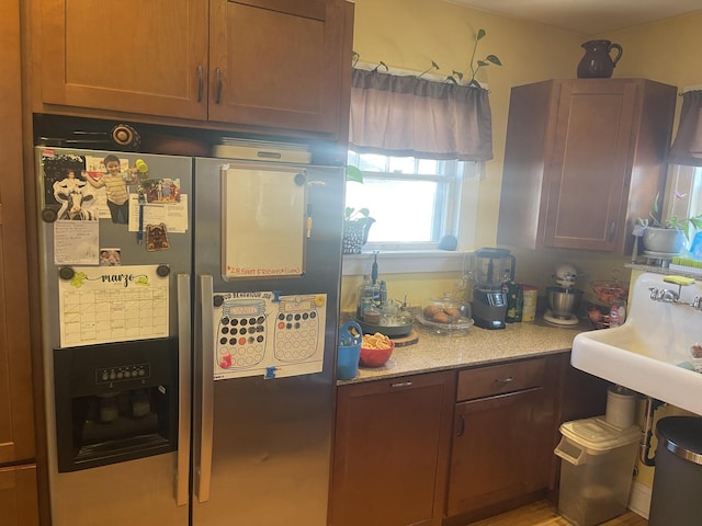 kitchen featuring a sink, stainless steel fridge, and light stone countertops