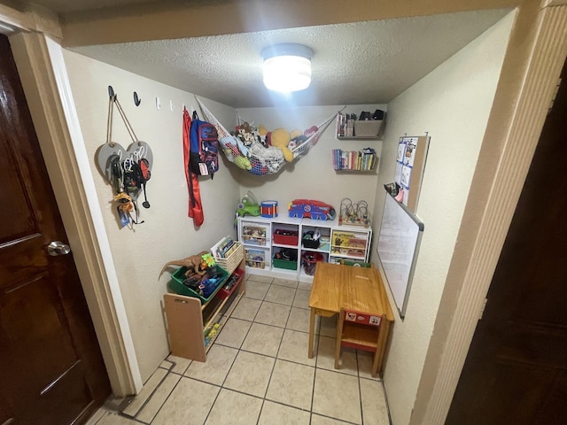 rec room featuring light tile patterned floors and a textured ceiling