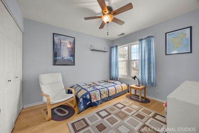 bedroom featuring a closet, visible vents, baseboards, and wood finished floors