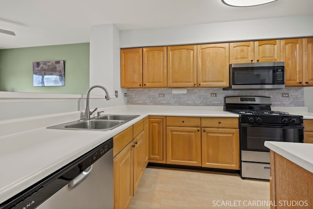 kitchen featuring a sink, decorative backsplash, appliances with stainless steel finishes, and light countertops