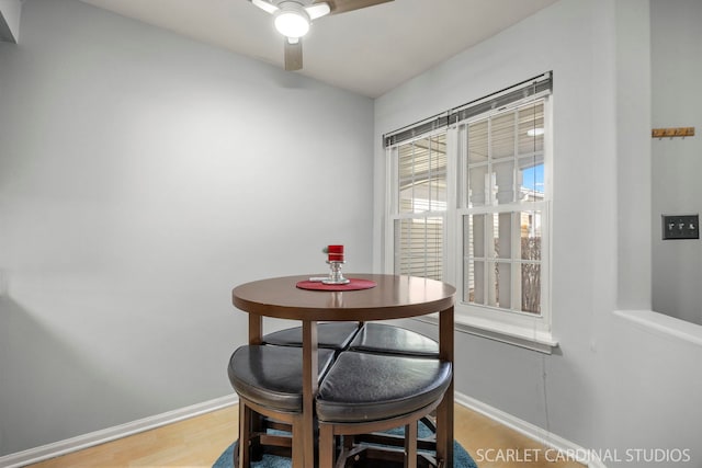 dining room with light wood-style flooring, a ceiling fan, and baseboards