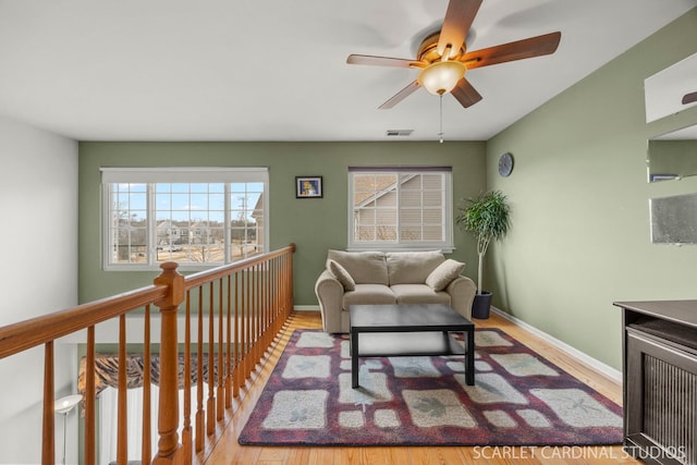 living area with visible vents, baseboards, and wood finished floors