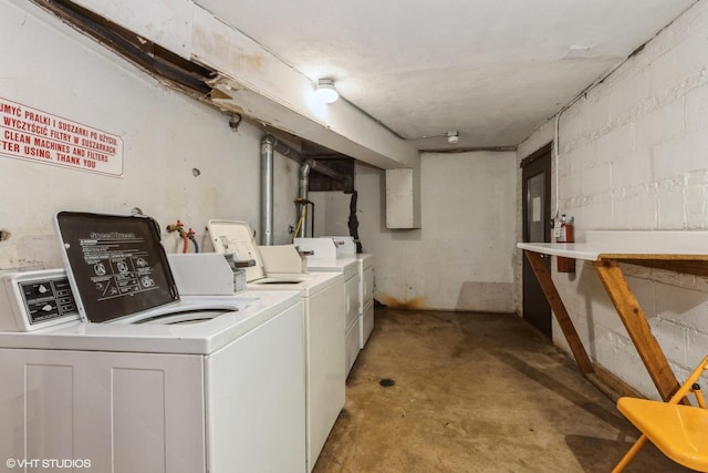 community laundry room featuring independent washer and dryer and concrete block wall