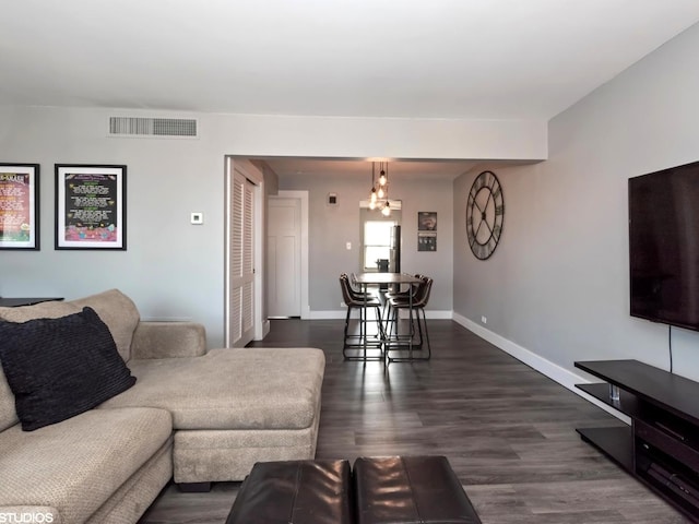 living room featuring visible vents, baseboards, and dark wood finished floors