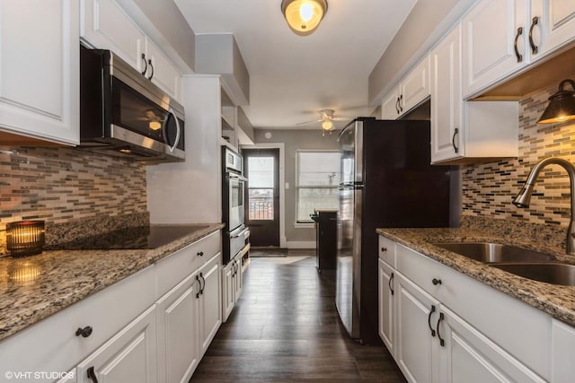 kitchen featuring dark wood-style floors, a sink, decorative backsplash, white cabinets, and appliances with stainless steel finishes