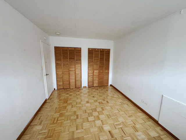 unfurnished bedroom featuring baseboards and two closets