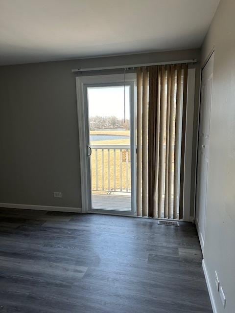 spare room featuring dark wood-style floors and baseboards