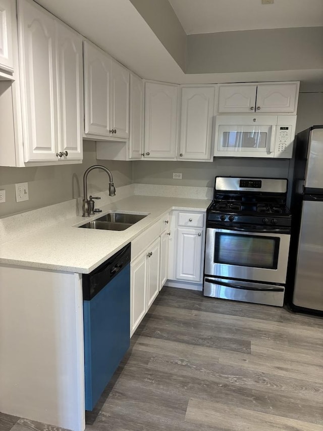 kitchen with dark wood-style floors, white cabinetry, stainless steel appliances, and a sink