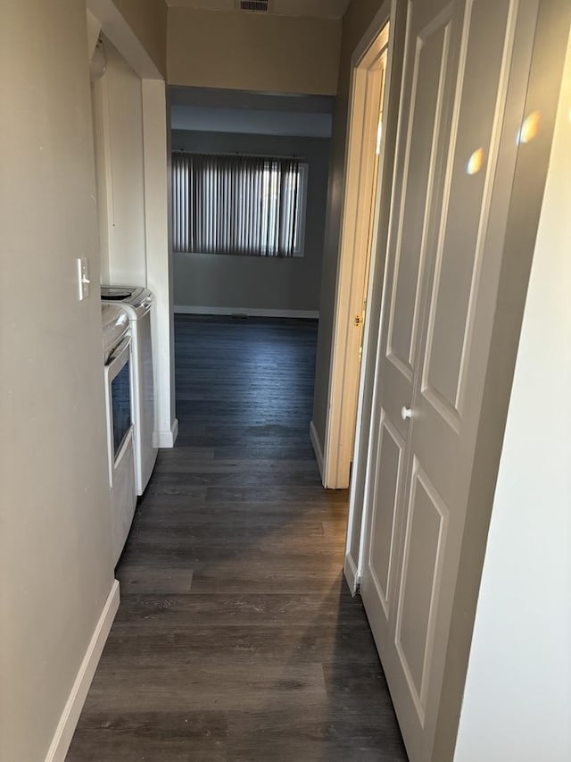 corridor featuring dark wood-type flooring, visible vents, and baseboards