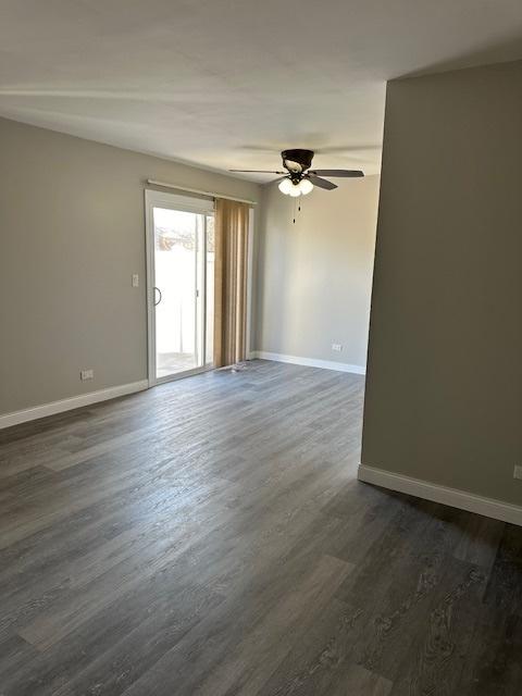 unfurnished room with baseboards, dark wood finished floors, and a ceiling fan