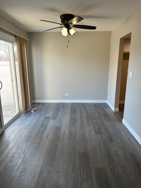 empty room featuring baseboards, dark wood-style floors, and a ceiling fan