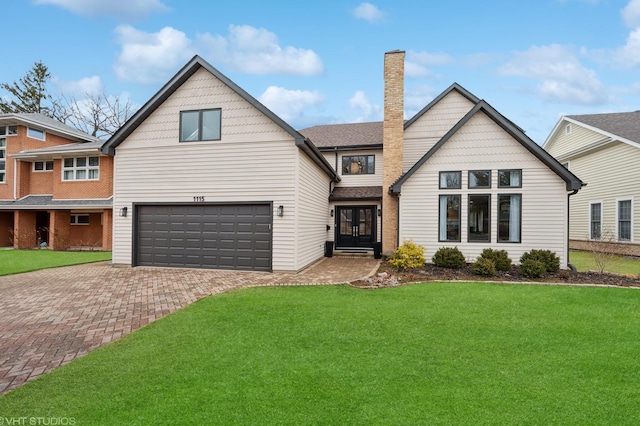 view of front of house featuring a front yard, decorative driveway, french doors, and an attached garage