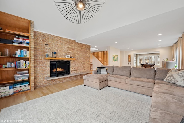 living room featuring recessed lighting, a brick fireplace, and wood finished floors