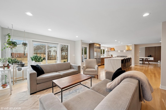 living area with recessed lighting, light wood-type flooring, and baseboards