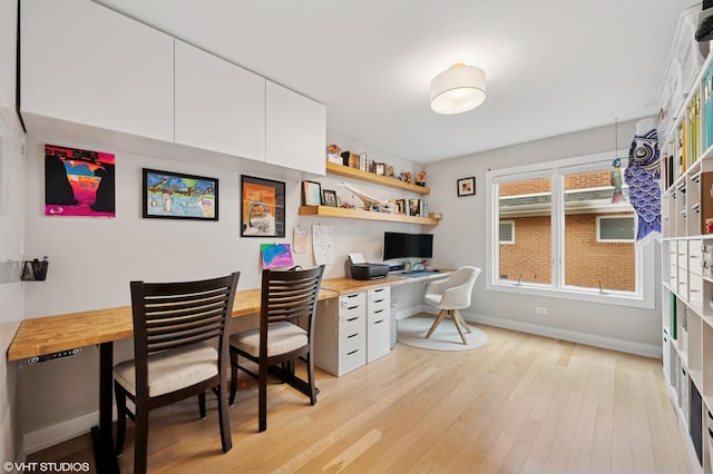 office featuring light wood finished floors, built in desk, and baseboards