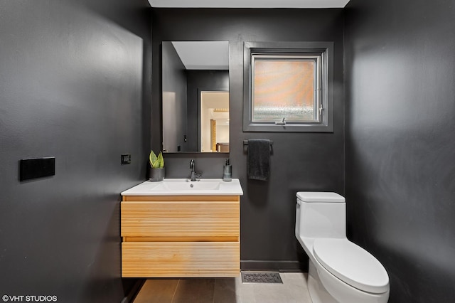 half bathroom with vanity, toilet, and baseboards