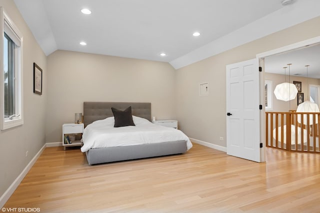 bedroom with light wood-style flooring, baseboards, and lofted ceiling