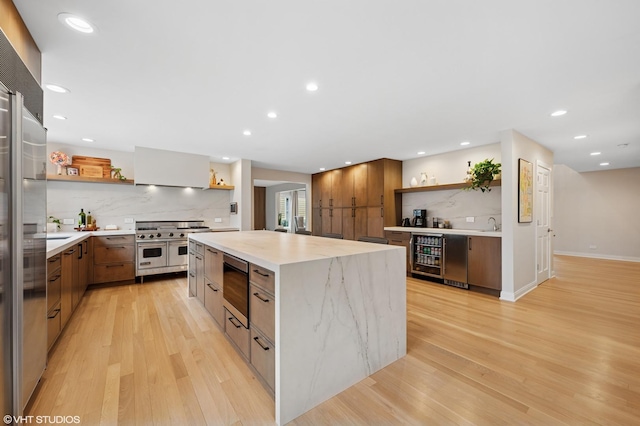 kitchen with open shelves, range with two ovens, light wood-style flooring, modern cabinets, and backsplash