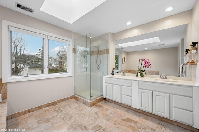 full bath featuring a stall shower, a skylight, visible vents, and a sink