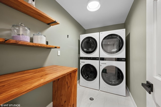 clothes washing area with laundry area, baseboards, stacked washer / drying machine, and marble finish floor